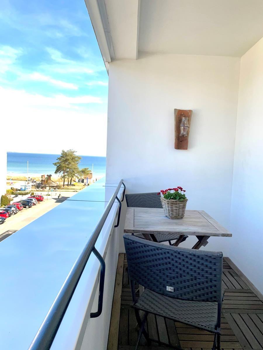 Balkon mit Tisch, Stühlen und Blick aufs Meer.