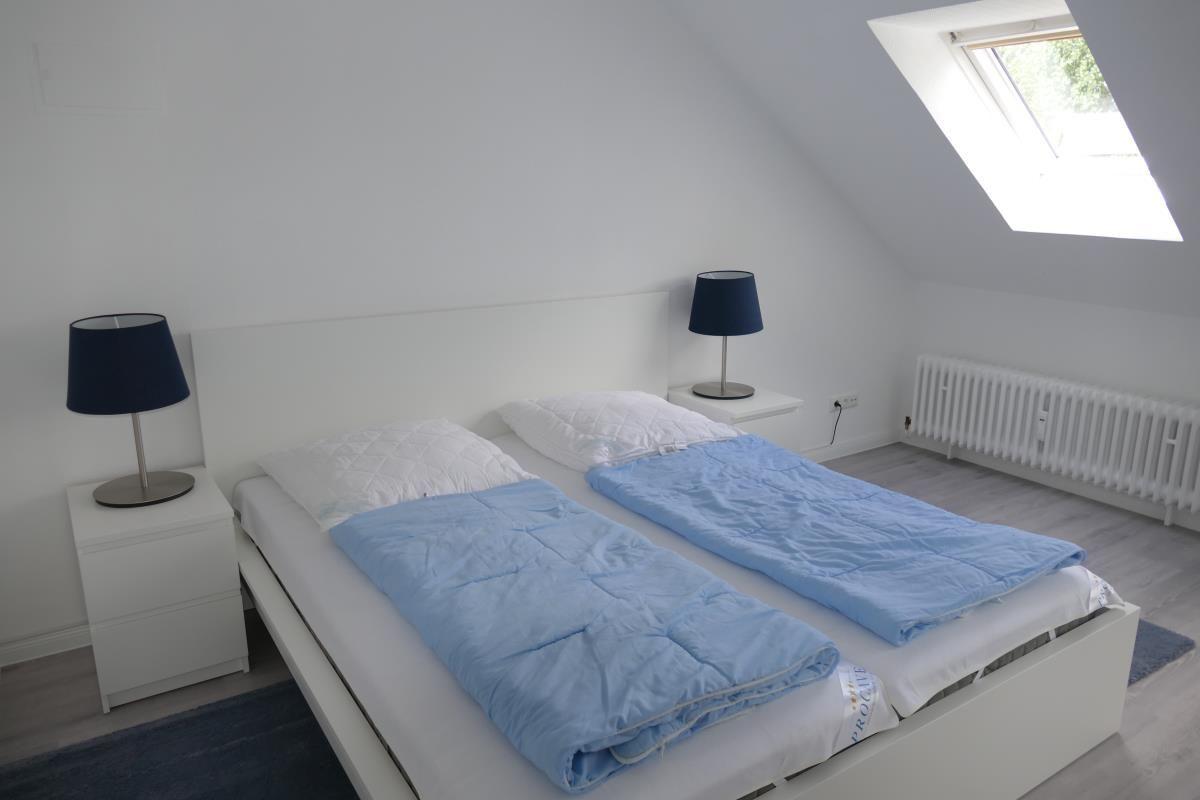 Schlafzimmer mit Doppelbett, zwei Nachttischen und Dachfenster.