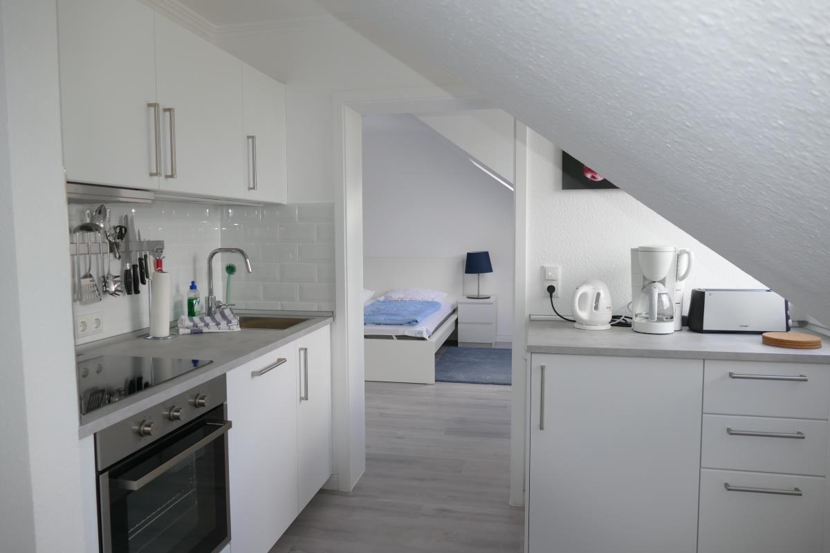 Küche mit Arbeitsfläche und Schlafzimmer im Hintergrund.