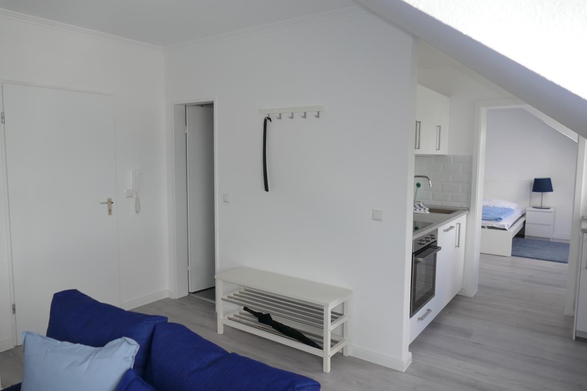 Wohnung mit Küche, Schlafzimmer und blauem Sofa.