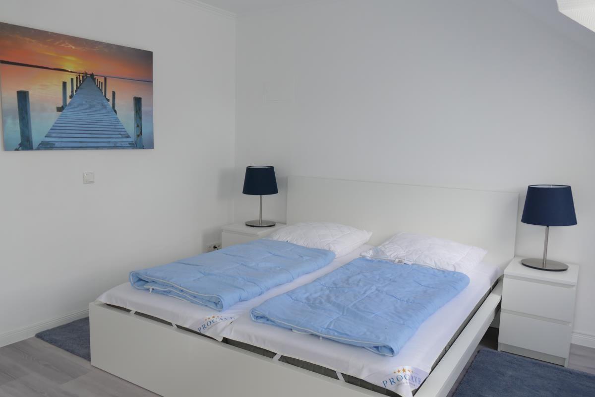 Schlafzimmer mit Doppelbett, zwei Nachttischen und Wandbild.