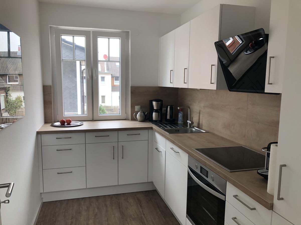 Kitchen with white cabinets, wooden countertop, and window overlooking outside.