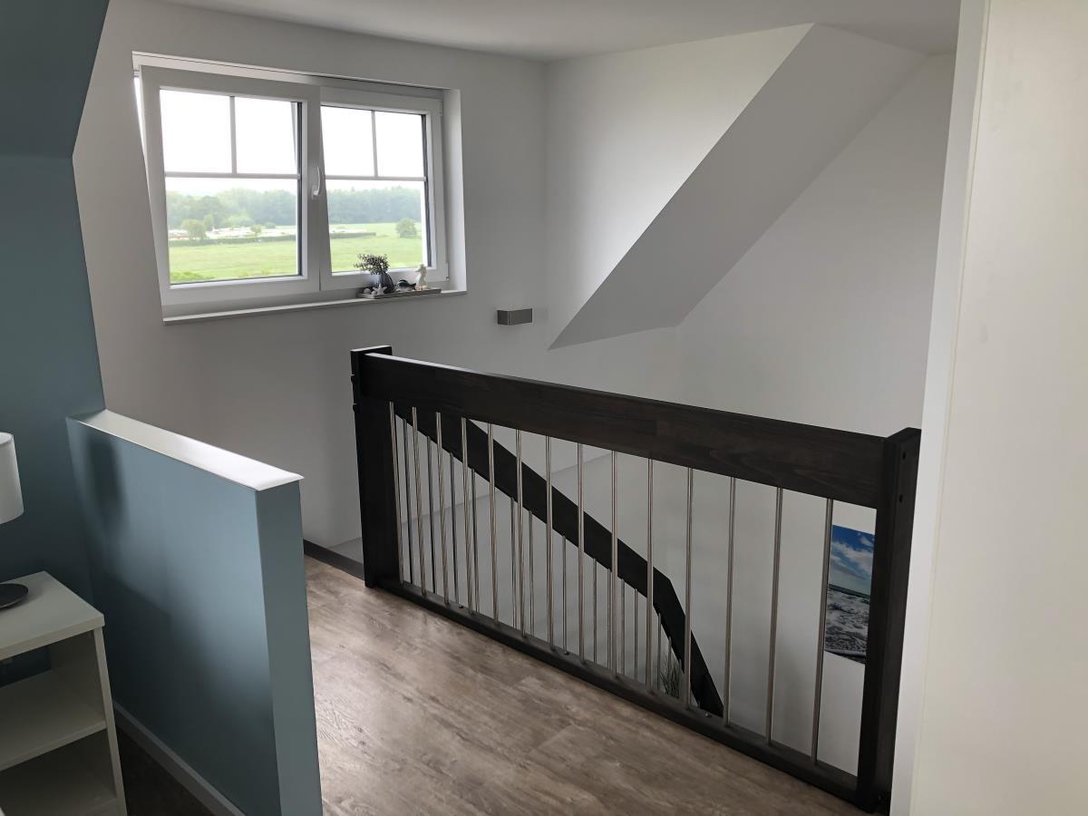 Staircase with glass railing and window overlooking greenery.