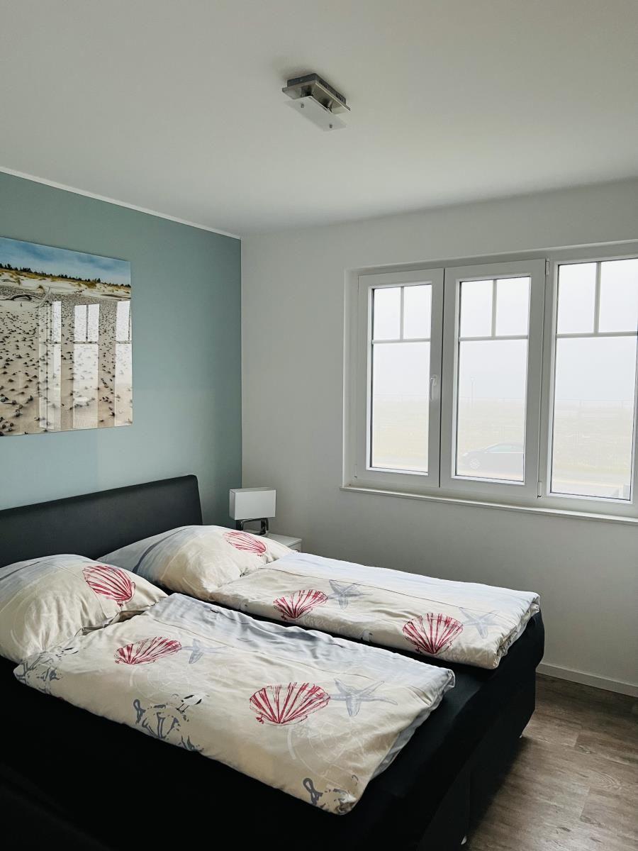 Bedroom with double bed, window, and wall picture.