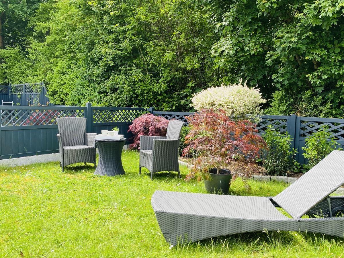Garten mit Liegestühlen, Tisch und Stühlen, Pflanzen und Zaun.
