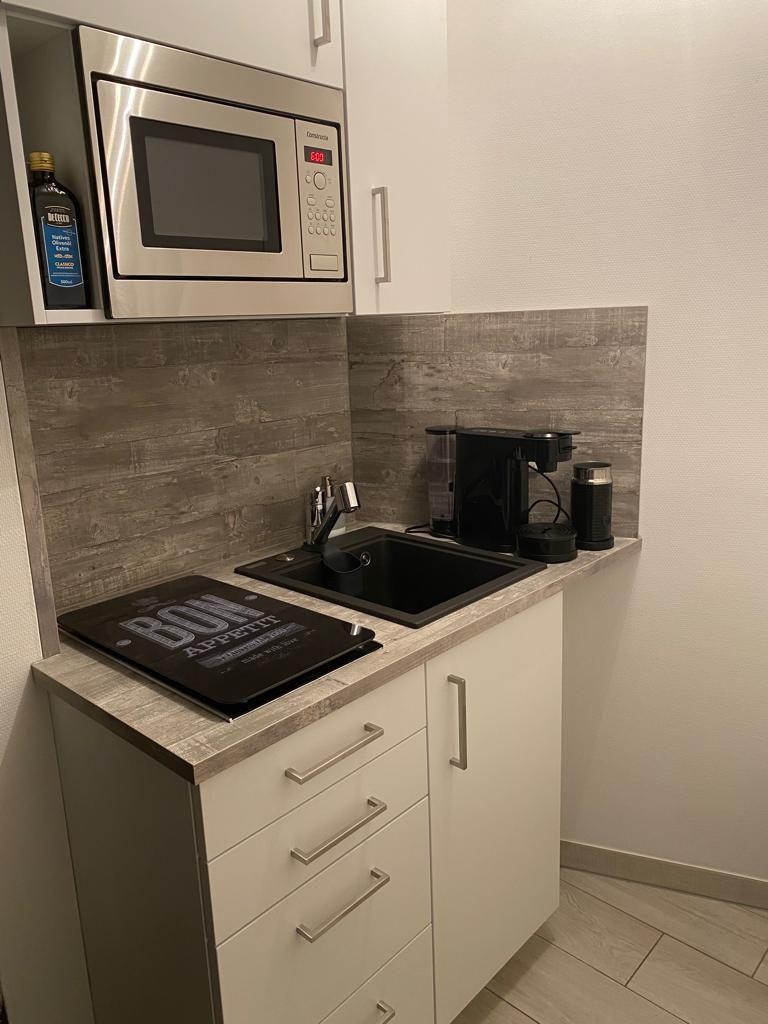 Küche mit Mikrowelle, Spüle und Kaffeemaschine.