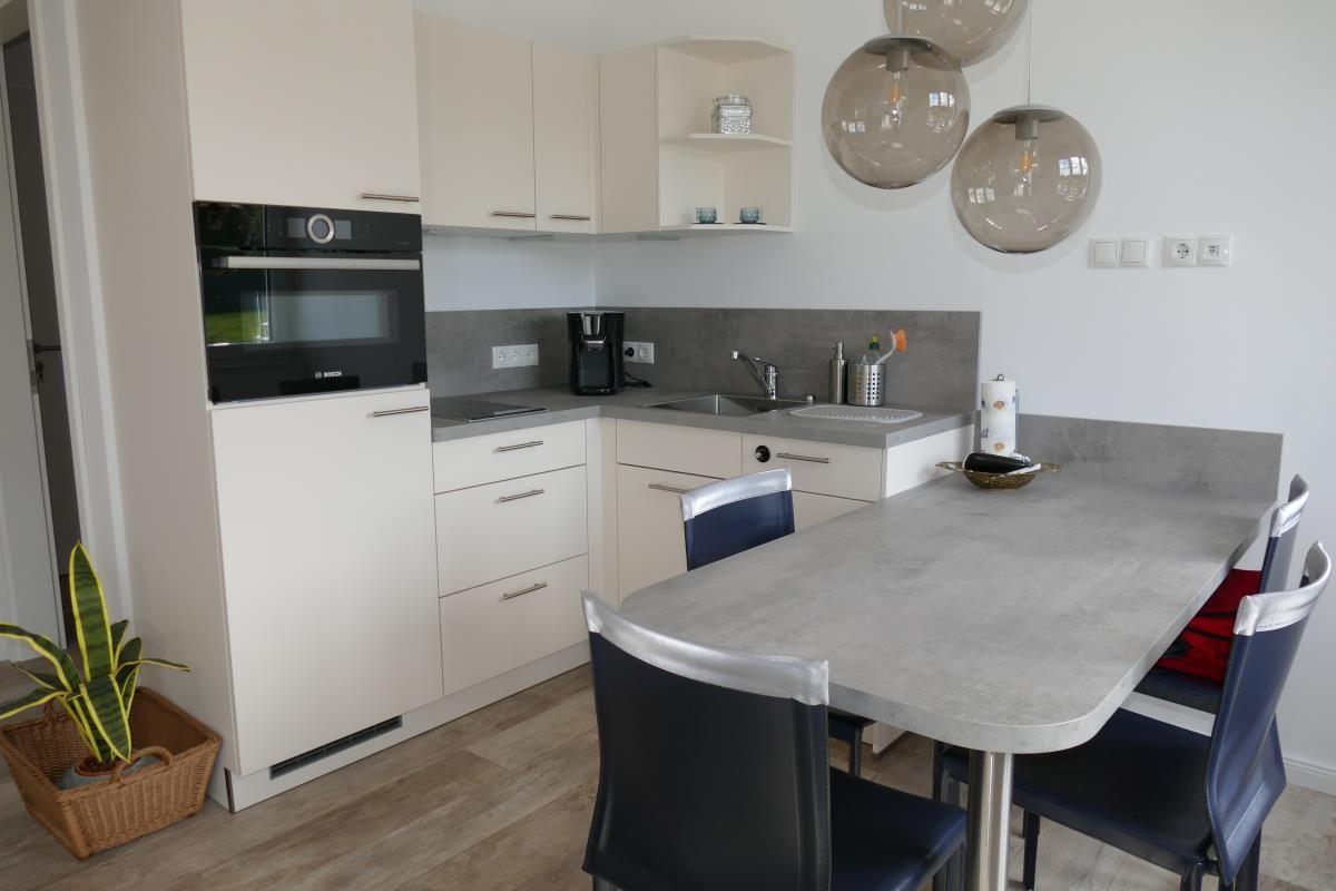 Kitchen with dining area, white cabinets, and gray worktop.