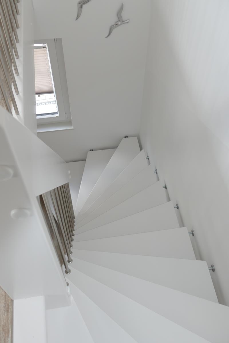 White spiral staircase with metal railing and skylight.