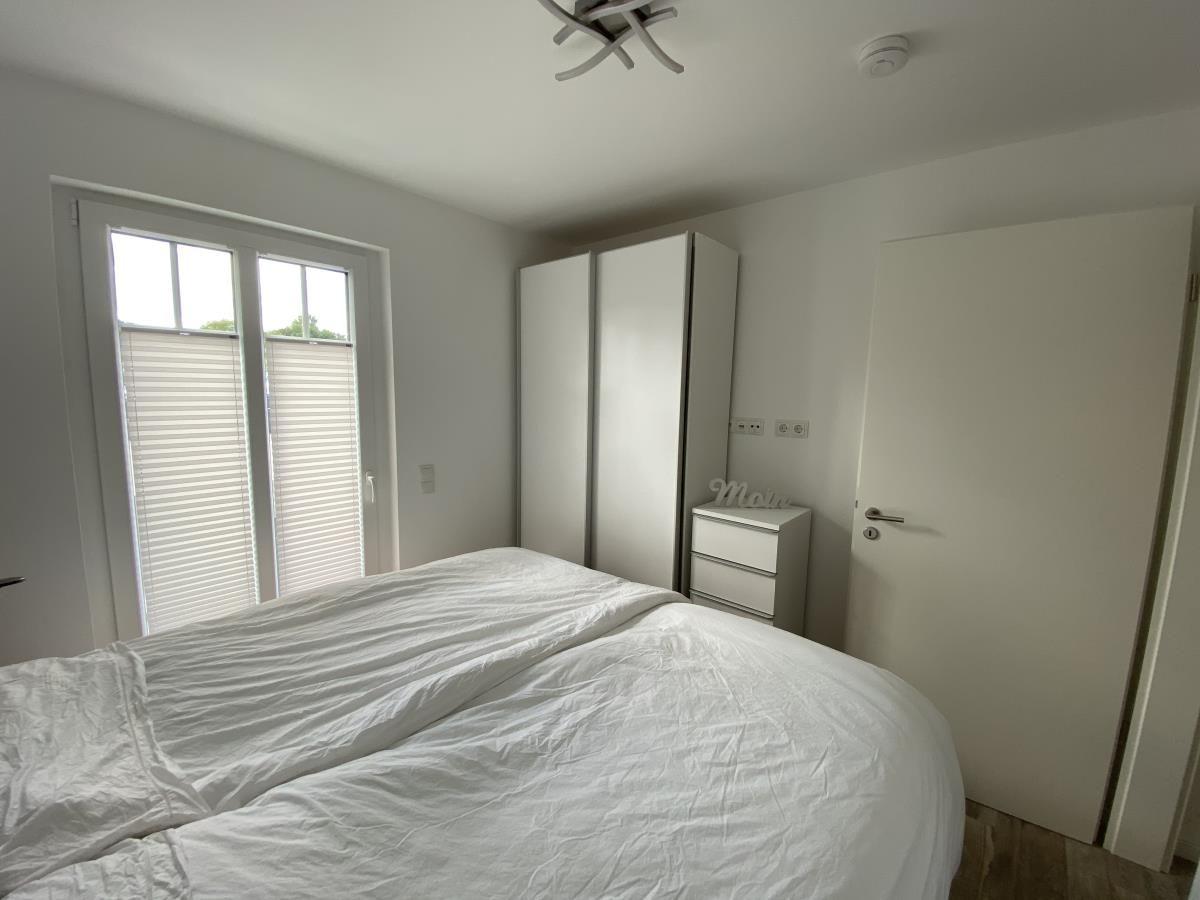 Bedroom with bed, wardrobe, and window with blinds.
