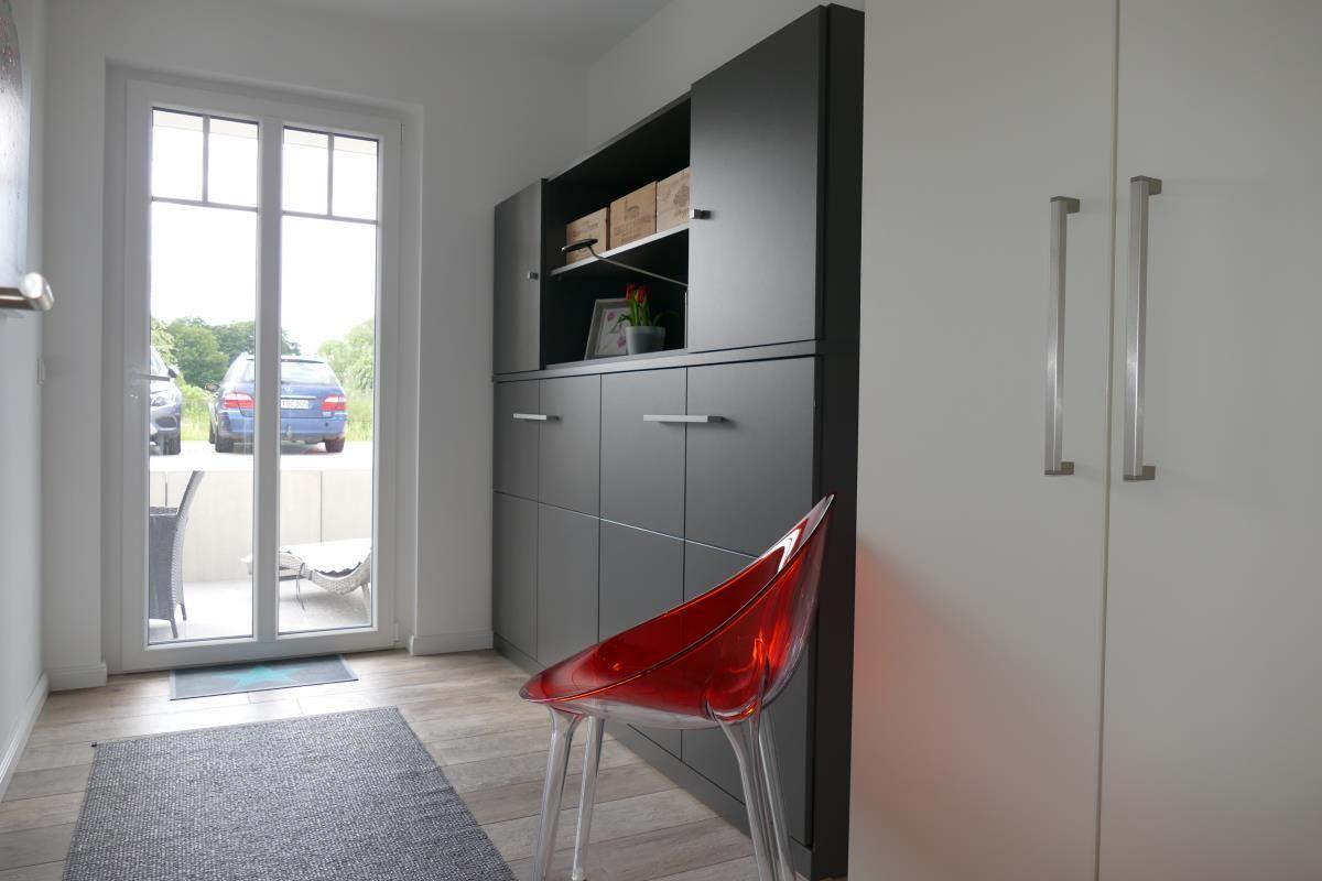 Entry area with cabinet, red chair, and terrace door.