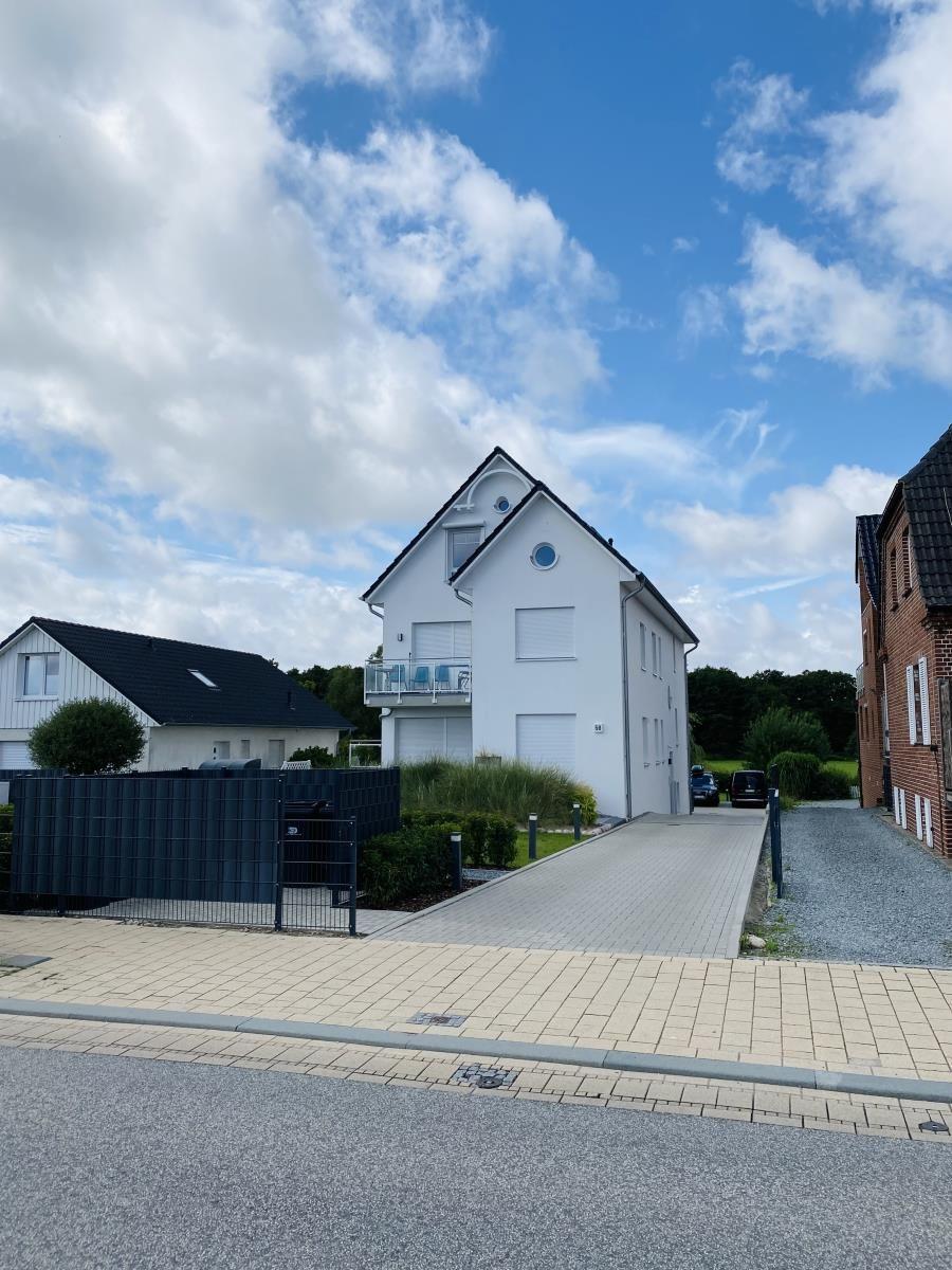 White single-family house with balcony and paved path.