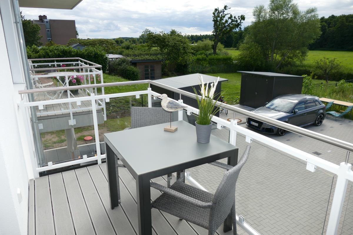 Terrace with table, chairs, and view of green areas.