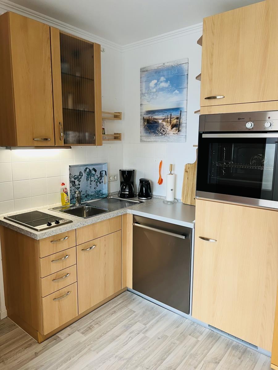 Küche mit Holzschränken, Spüle, Herd, Kühlschrank und Backofen.