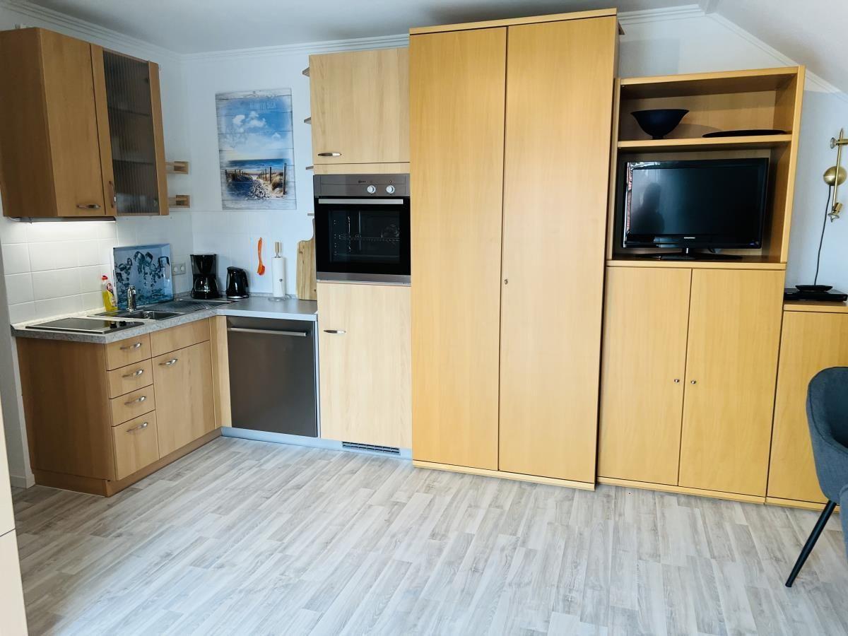 Küche mit Holzmöbeln, Spülmaschine und eingebauter Mikrowelle.