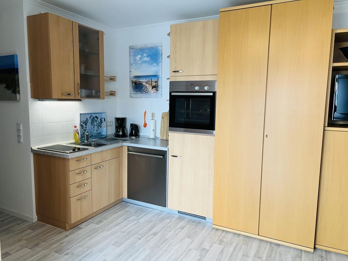 Küche mit Holzschränken, Spüle, Backofen und Kühlschrank.