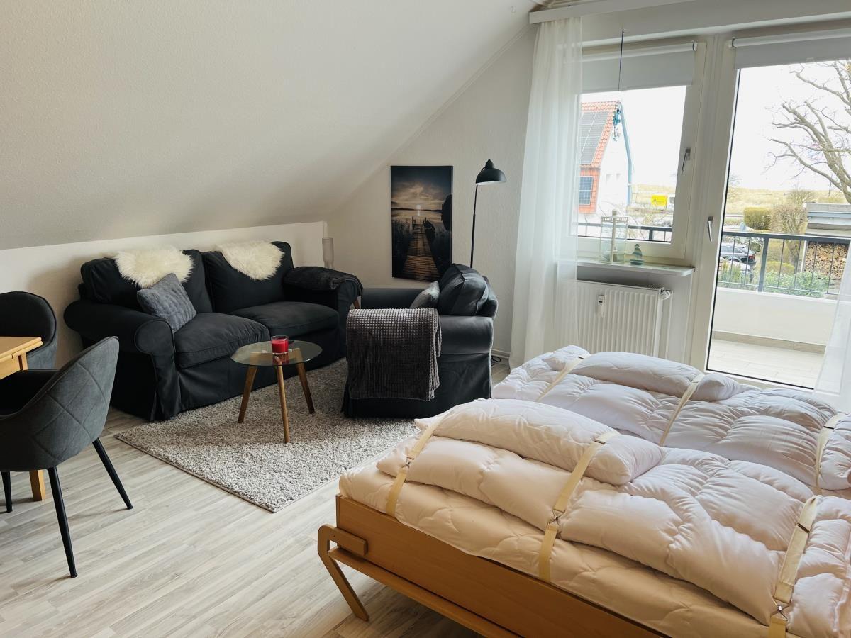 Schlafzimmer mit Bett, Sofa und Balkonansicht.