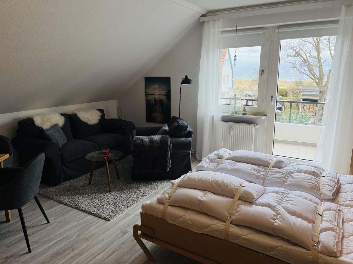 Schlafzimmer mit Schlafcouch, Sitzbereich und Balkonansicht.