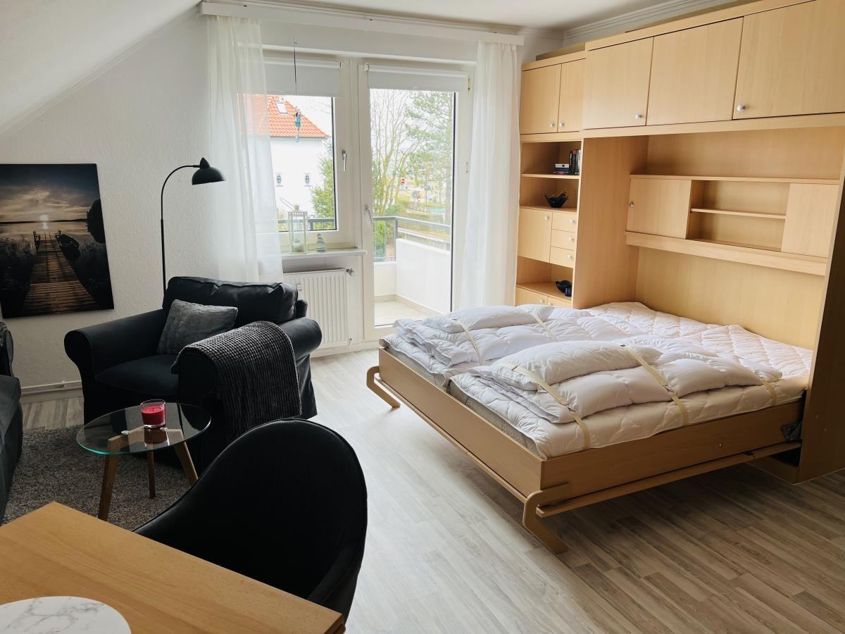 Schlafzimmer mit Klappbett und integriertem Schrank. Fenster mit Blick auf Balkon.