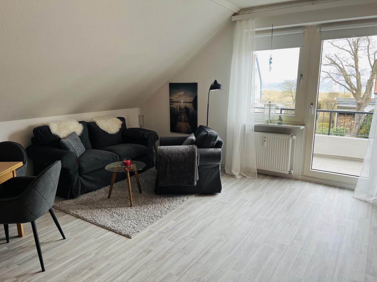 Wohnraum mit Sofa, Sessel und Balkonansicht