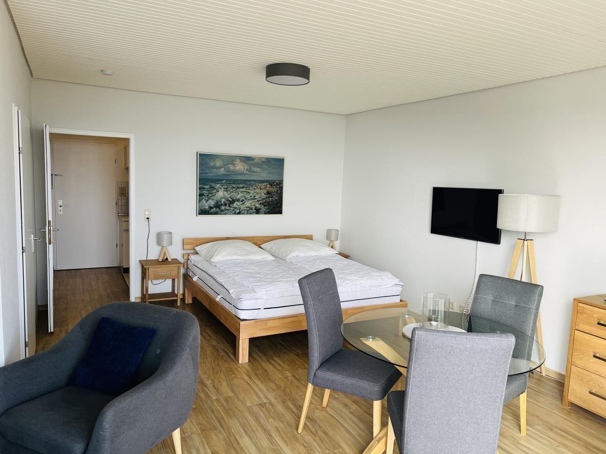 Zimmer mit Doppelbett, Esstisch, Fernseher und Wandbild.