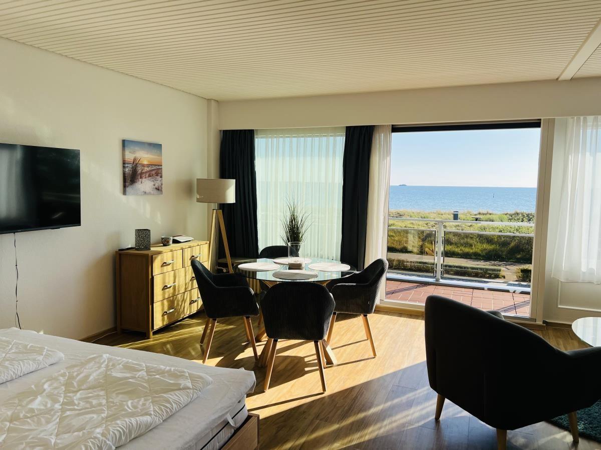Schlafzimmer mit Blick aufs Meer und Essbereich mit Tisch und Stühlen.