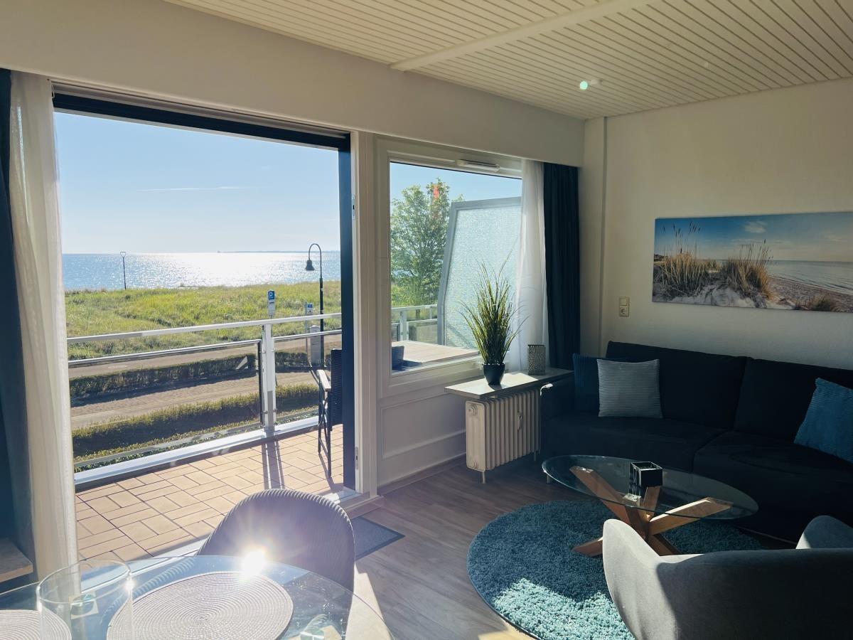 Wohnzimmer mit Meerblick, Sofa, Tisch und Balkon.