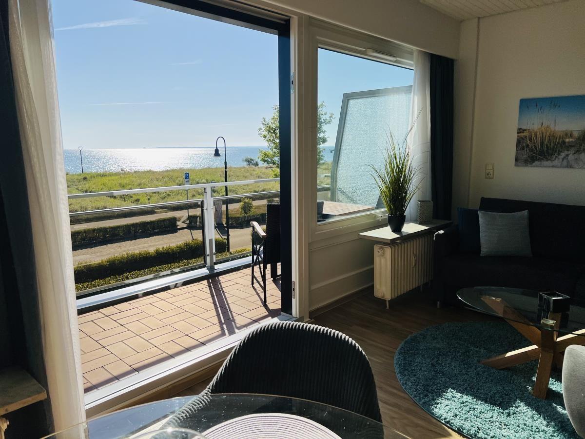 Wohnbereich mit Blick aufs Meer und Balkon mit Sitzgelegenheit.