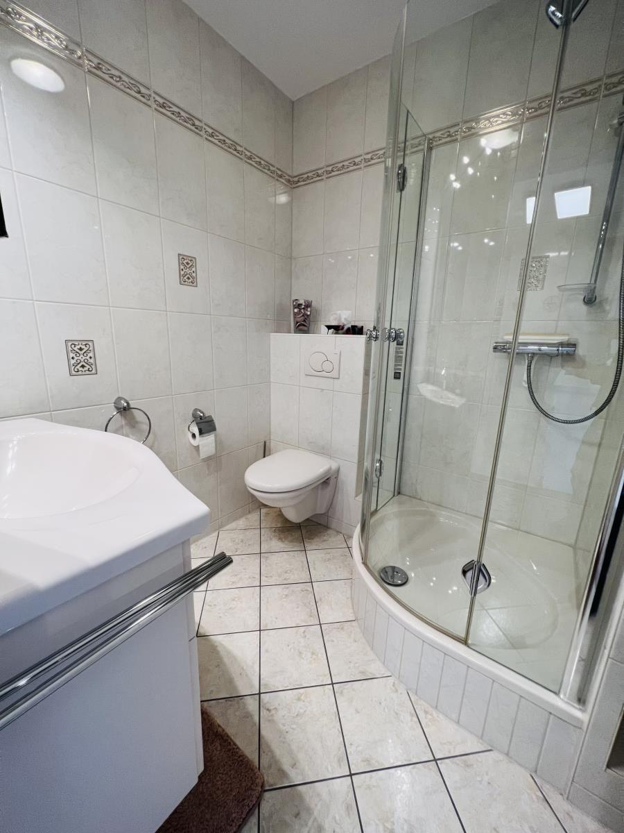 Badezimmer mit Dusche, Toilette und Waschbecken.