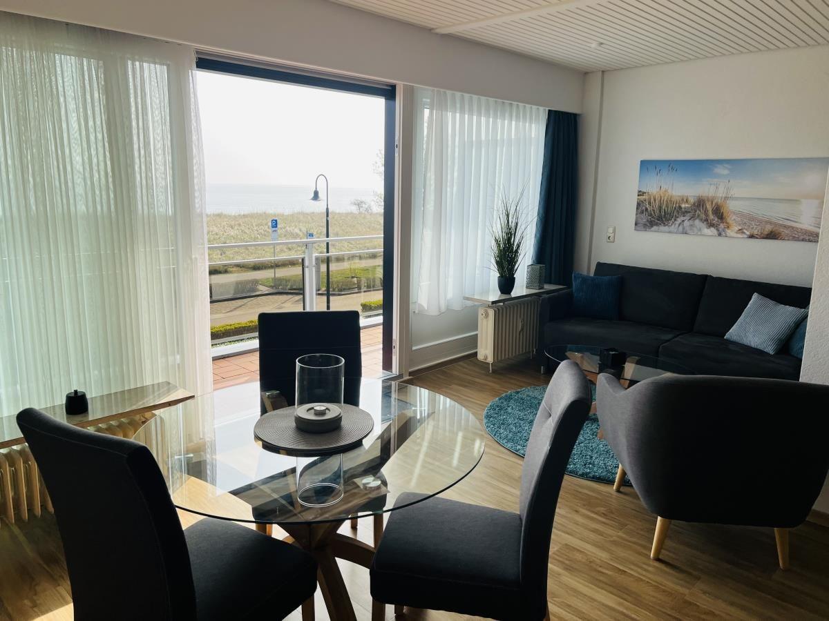 Wohn- und Essbereich mit Blick aufs Meer. Sofa, Tisch und Stühle.