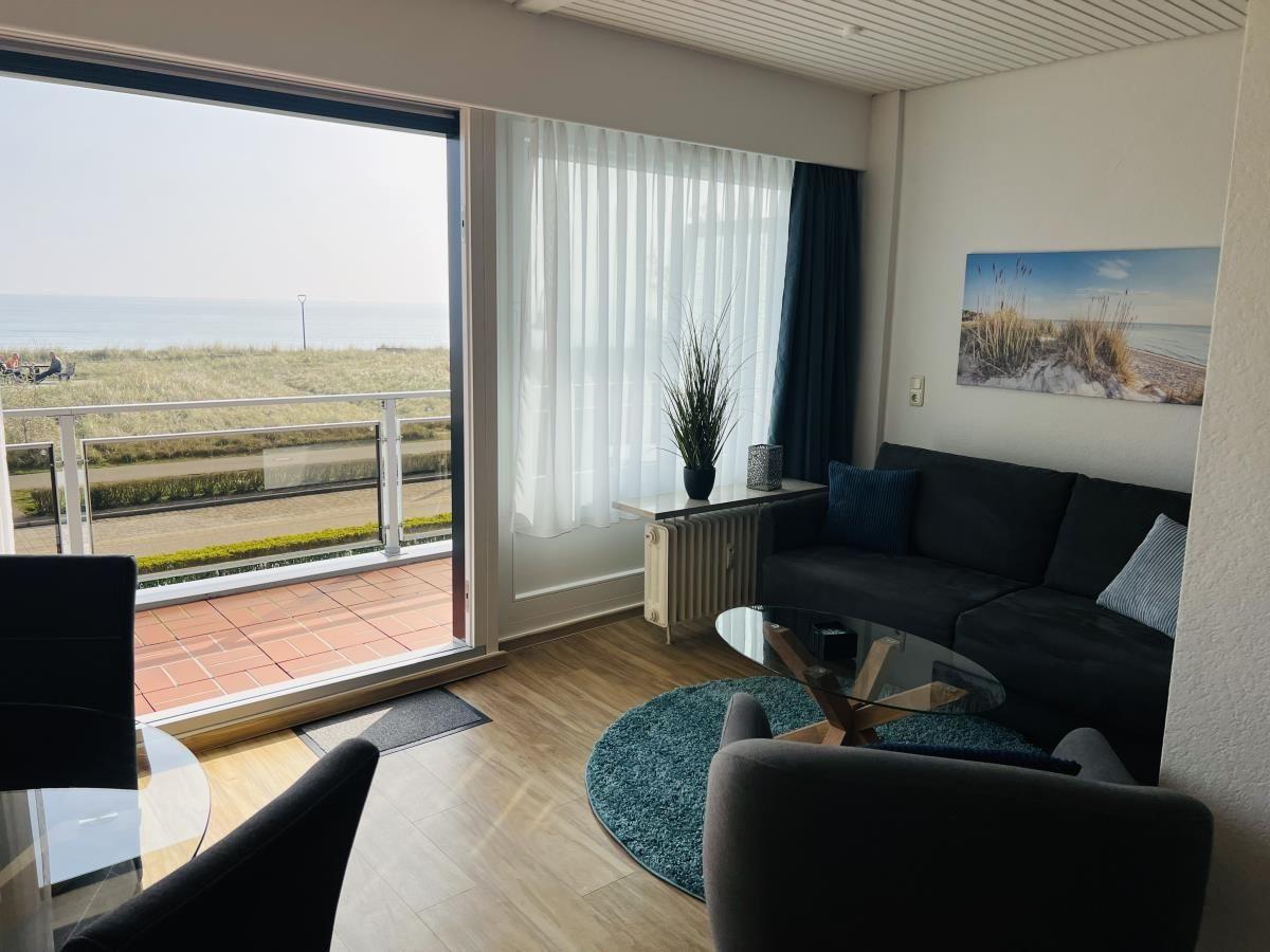 Wohnzimmer mit Blick aufs Meer und Balkon. Sofa, Sessel und Tisch.