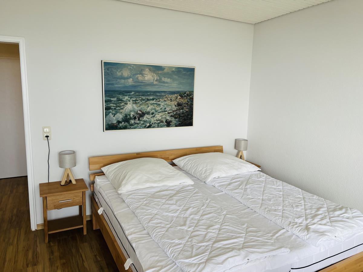 Schlafzimmer mit Doppelbett, Nachttisch und Wandbild.