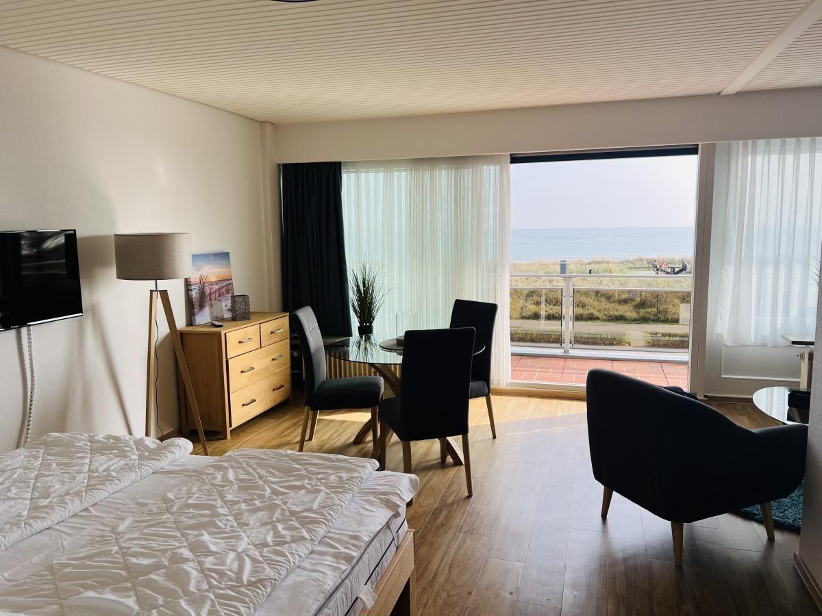 Schlafzimmer mit Blick aufs Meer und Essbereich mit Tisch und Stühlen.