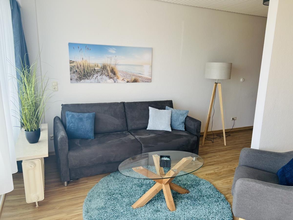 Wohnzimmer mit Sofa, Glas-Tisch und Wandbild