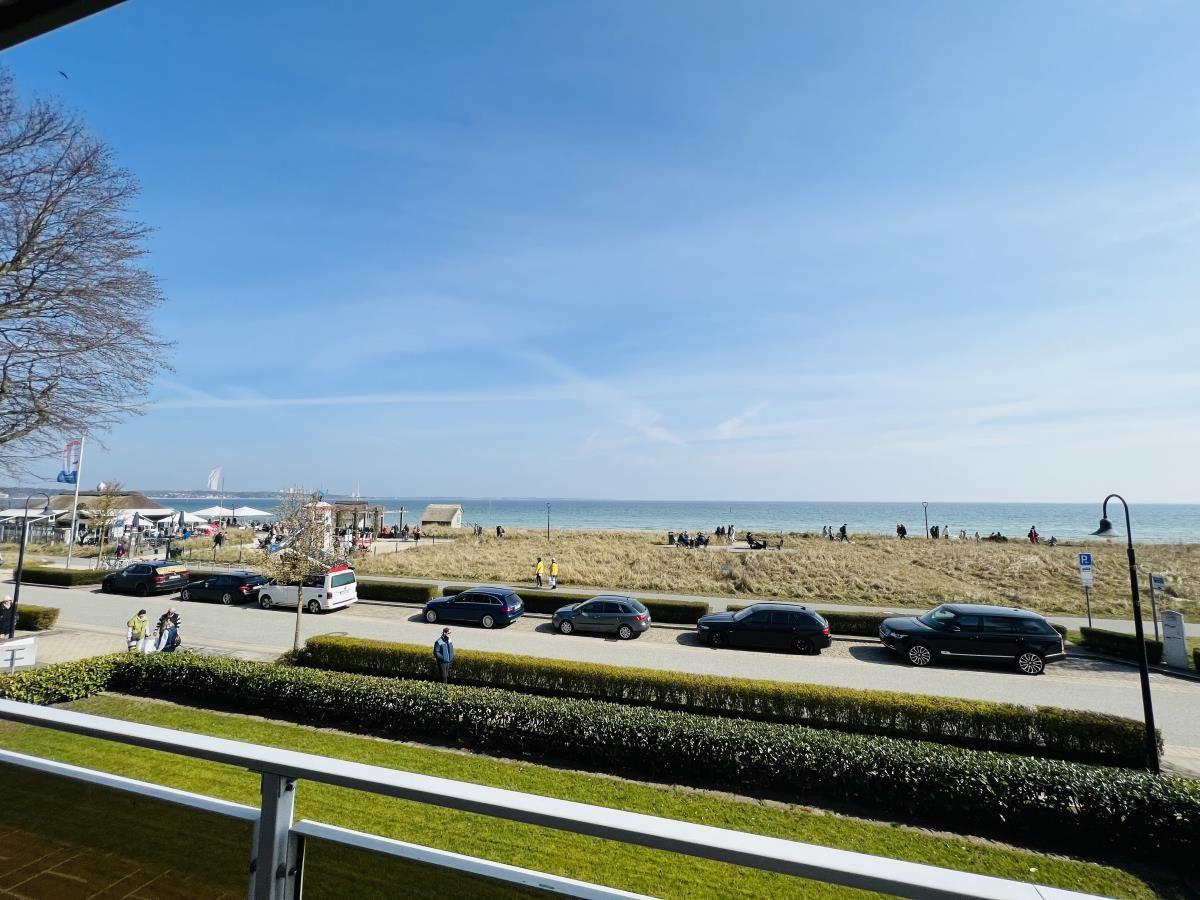 Blick auf Strand mit Parkplatz und Grünflächen unter blauem Himmel