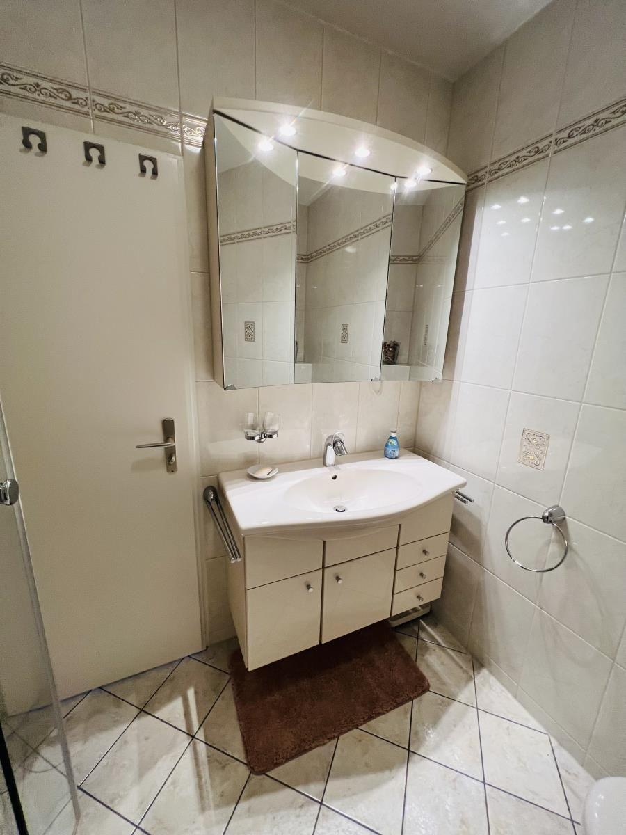 Badezimmer mit Waschbecken, Spiegel und Dusche