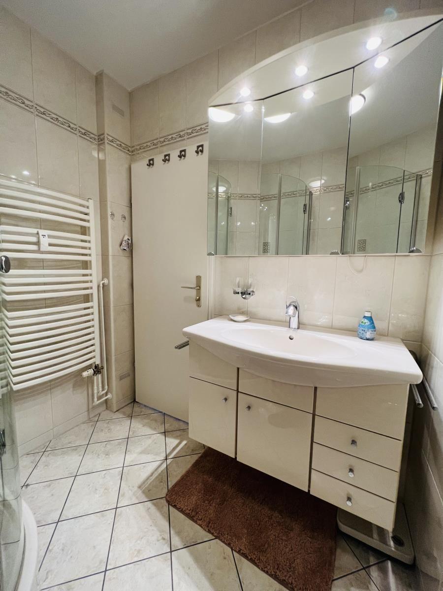 Badezimmer mit Waschbecken, Spiegel und Dusche