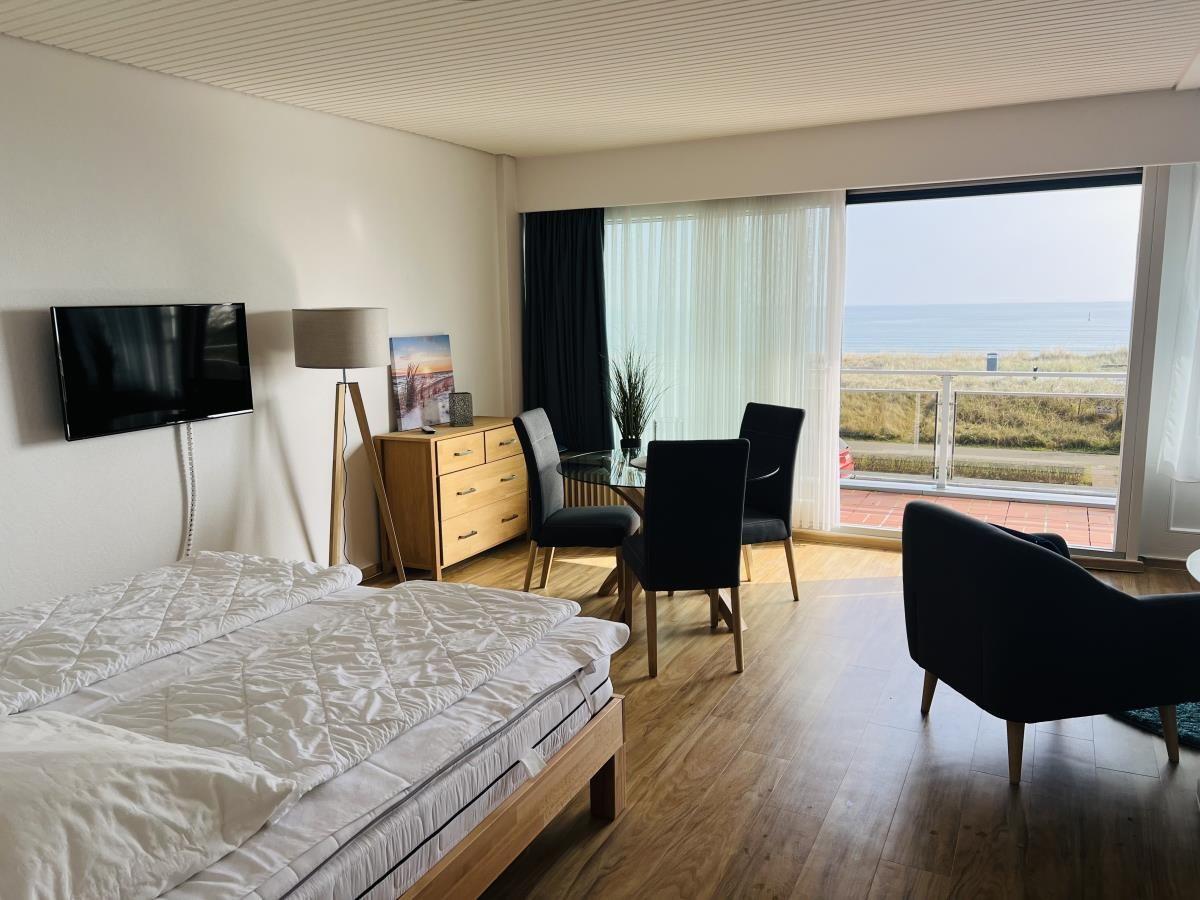 Schlafzimmer mit Blick aufs Meer und Essbereich mit Tisch und Stühlen.