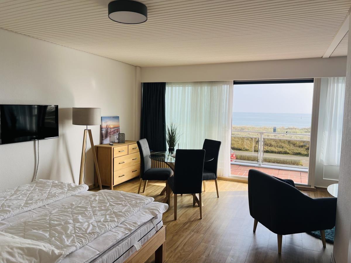 Schlafzimmer mit Blick aufs Meer und Essbereich mit Tisch und Stühlen.
