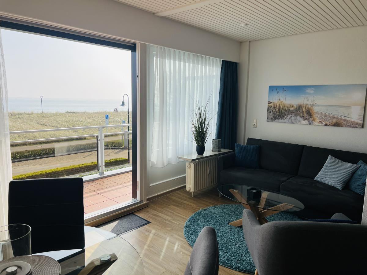 Wohnzimmer mit Blick auf Strand und See. Sofa, Tisch und Sessel.