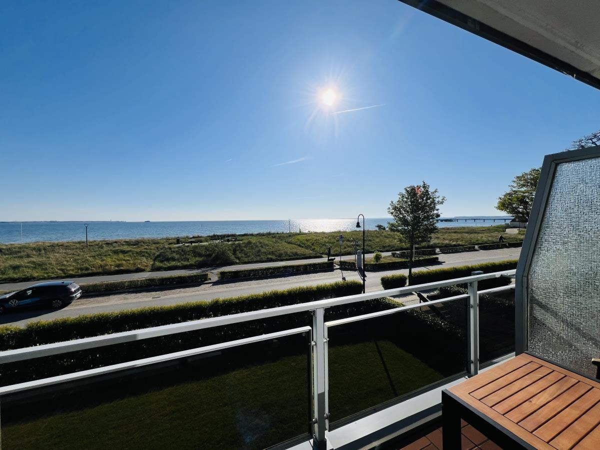 Balkon mit Blick auf Meer und Straße unter blauem Himmel.