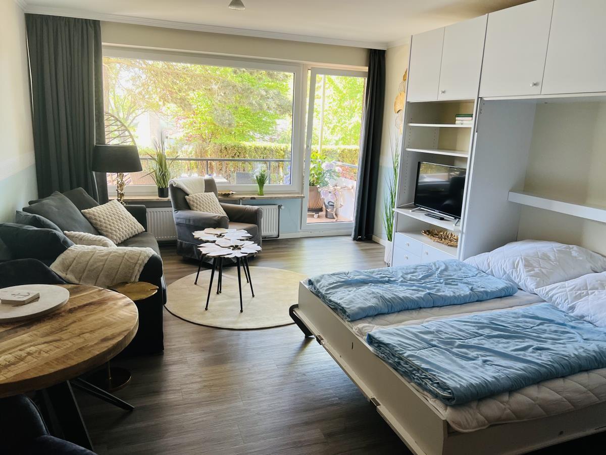 Ein Schlafzimmer mit Bett, TV und Balkonzugang.