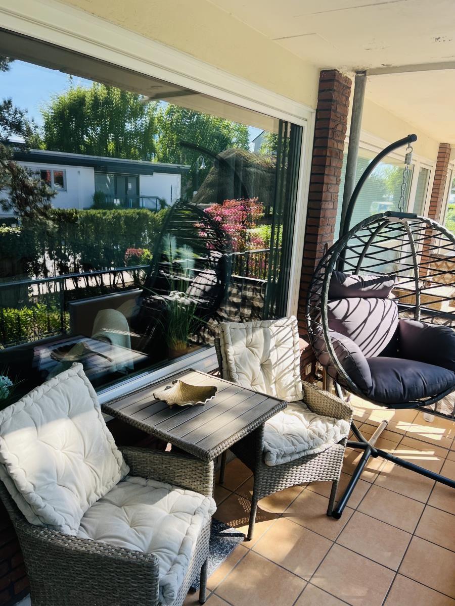 Terrasse mit Sitzgruppe, Hängesessel und Blick auf Garten.