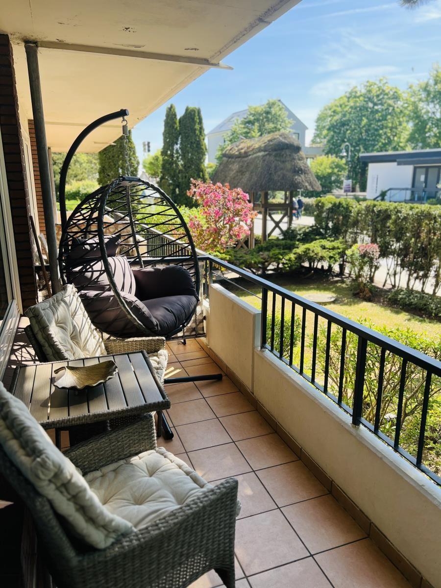 Terrasse mit Hängesessel und Sitzgruppe, Blick auf grünen Garten mit Hütte.