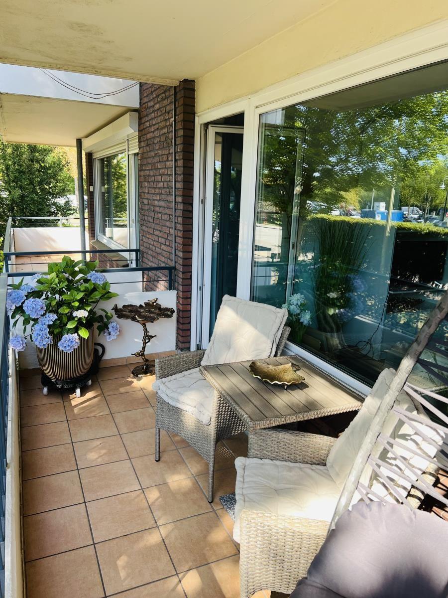 Terrasse mit Sitzgruppe, Pflanzen und Glasfront zur Wohnung.