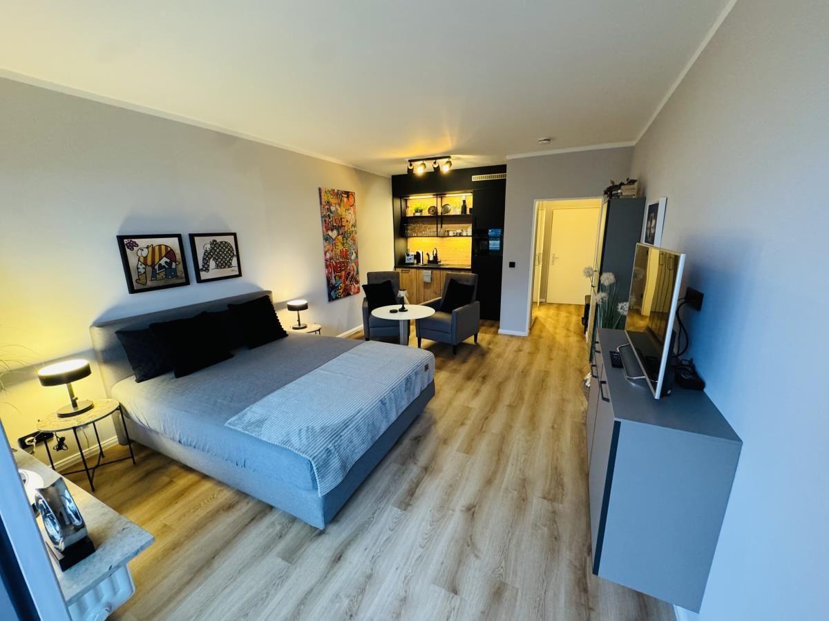 Schlafzimmer mit Bett, Sitzbereich und TV-Möbel.