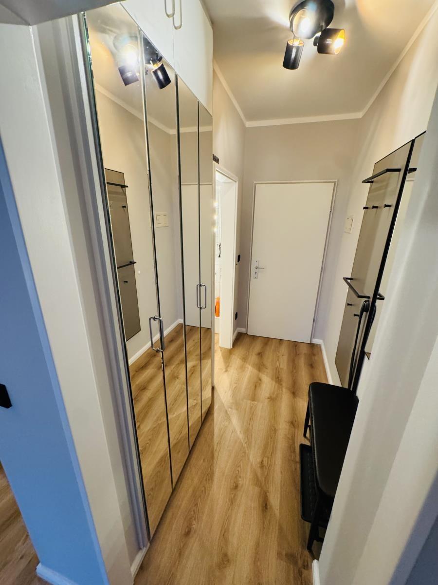 Flur mit Spiegelschrank, Holzboden und Deckenleuchten.
