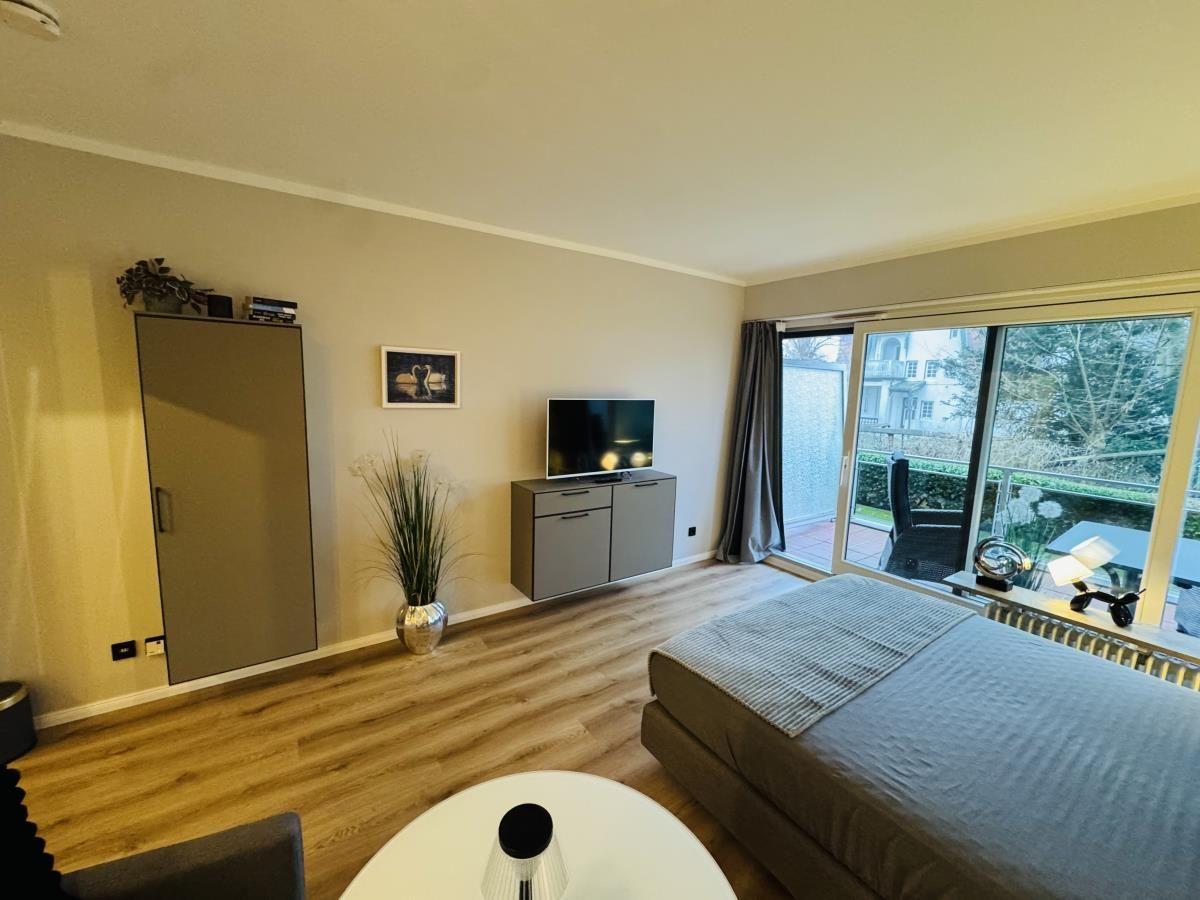 Schlafzimmer mit Bett, TV und Balkonansicht