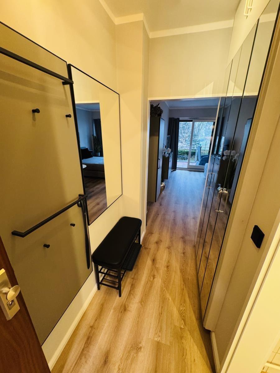 Flur mit Spiegelschrank, Sitzbank und Blick in Wohnbereich mit Terrasse.