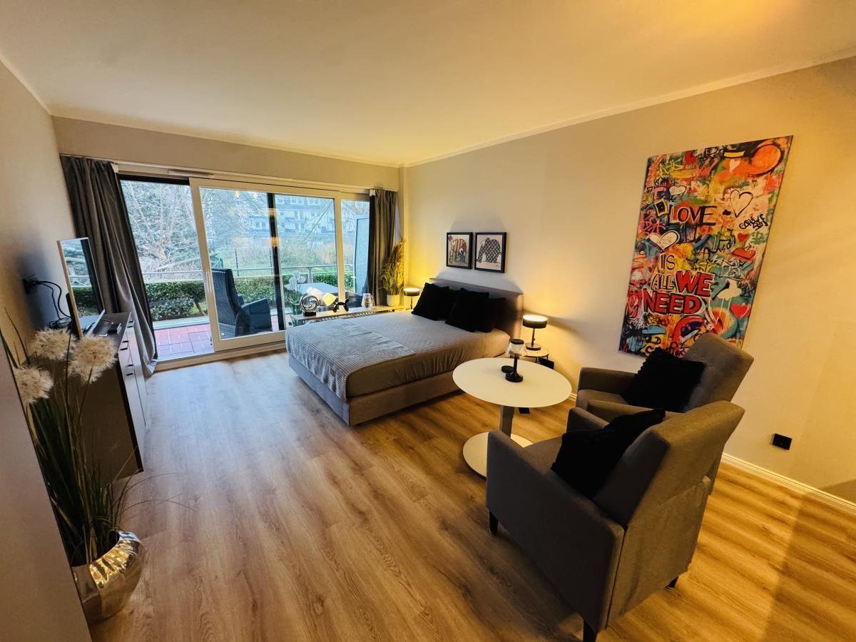 Schlafzimmer mit Bett, Sessel und Balkonansicht.