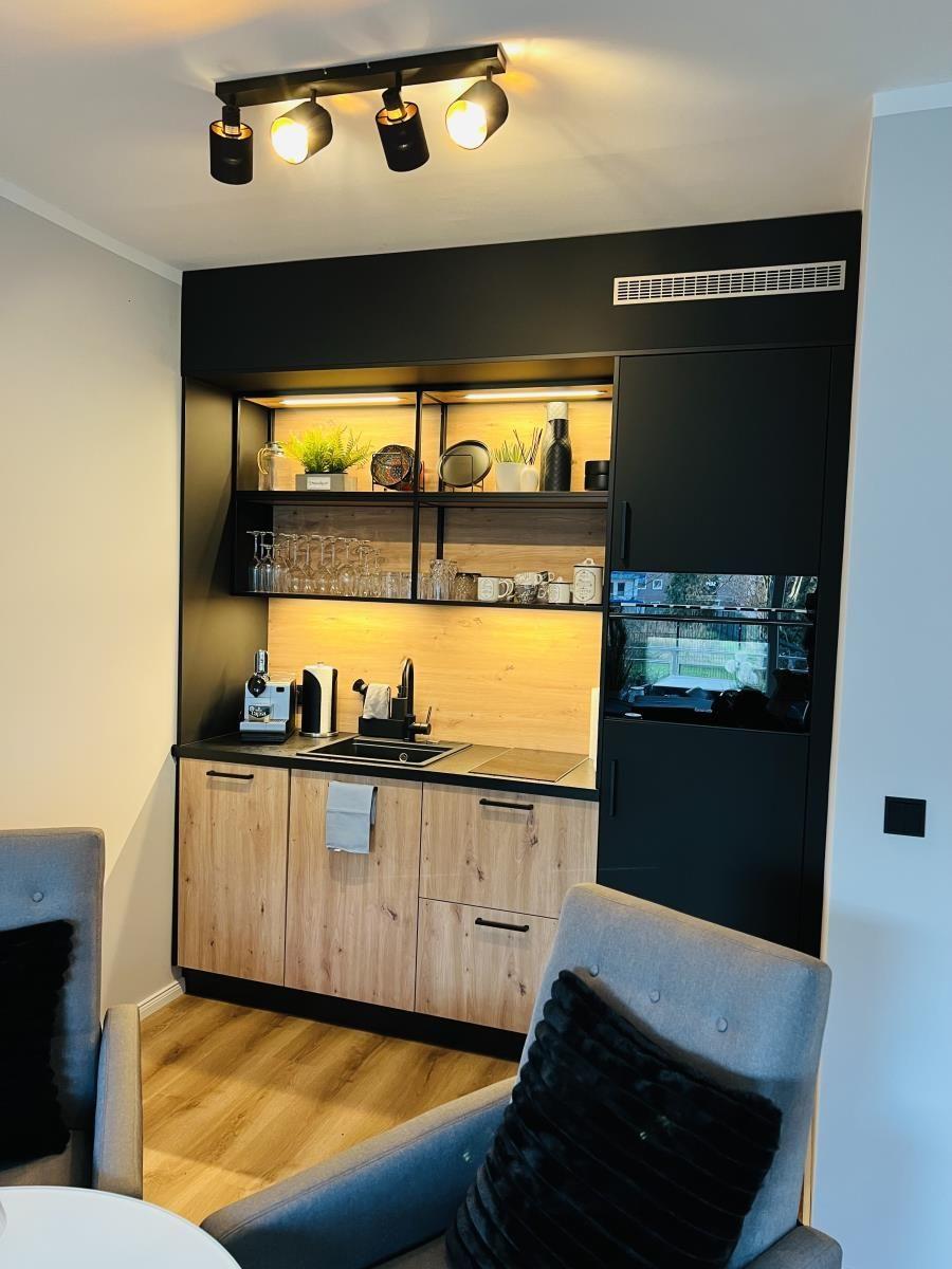 Küchenbereich mit Holzfronten, Edelstahlspüle und integriertem Kühlschrank.